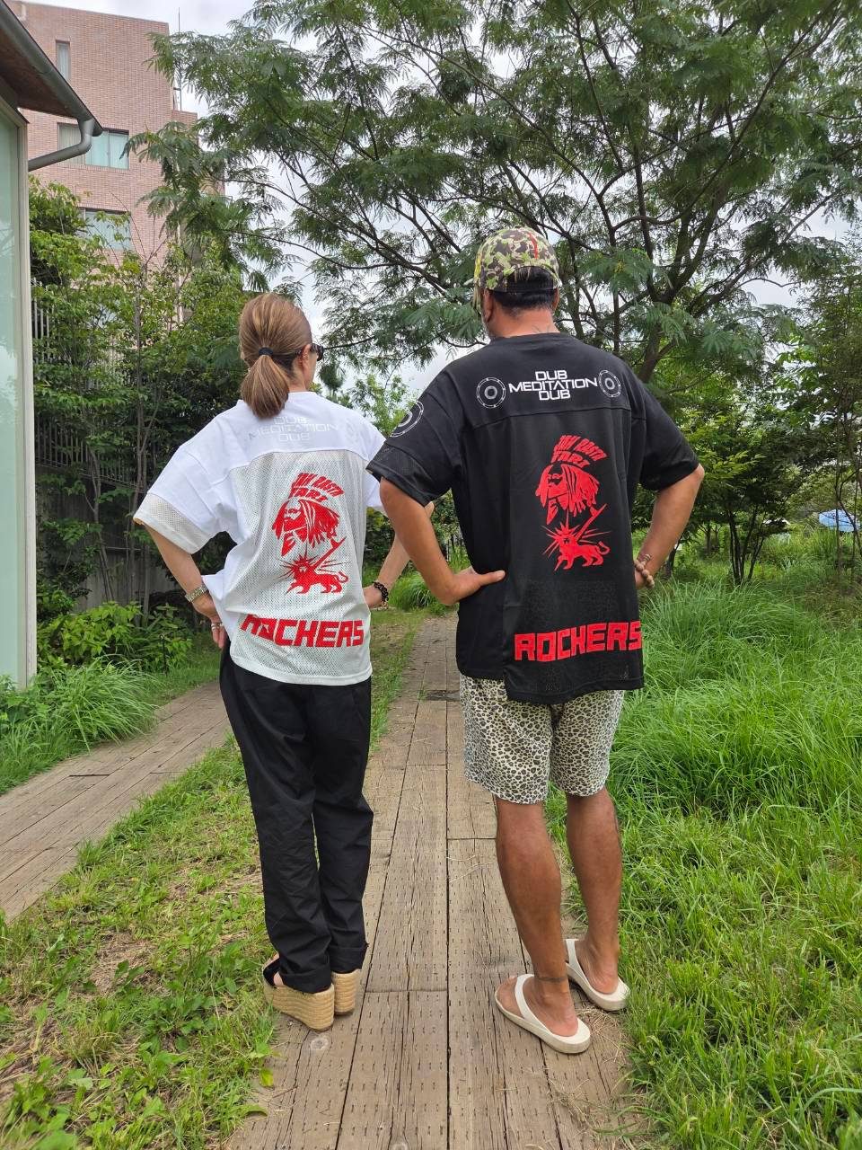 屋外での、ROCKERS Tシャツを着た二人の後ろ姿